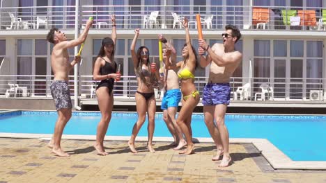 felices jóvenes amigos alegres bailando y divirtiéndose en la piscina. fiesta en la piscina de verano con pistolas de agua.