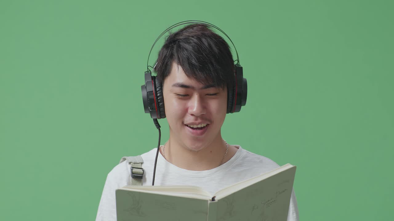 청년 이 헤드폰 을 들고 책 을 읽고 있다