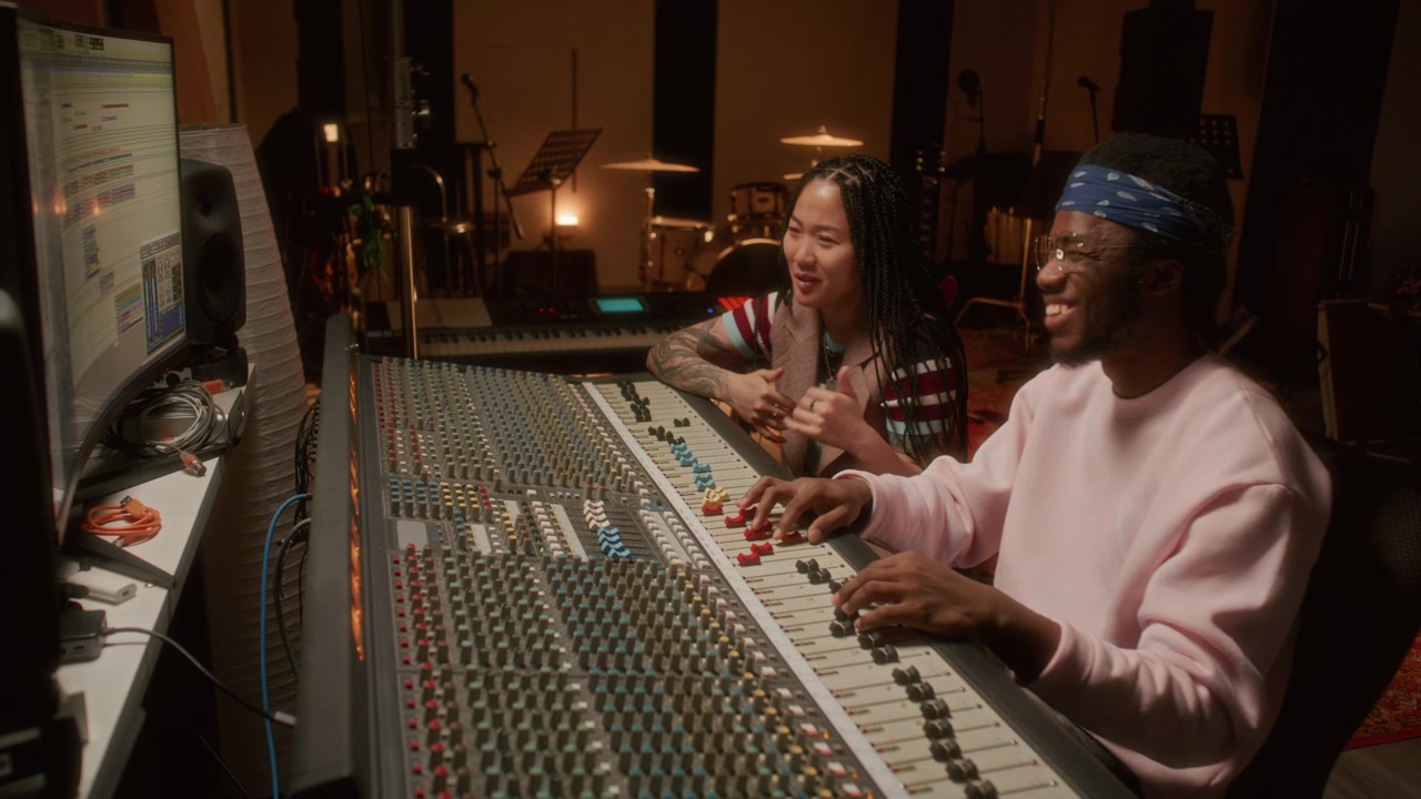 Diverse Colleagues Smiling while Mixing Tracks in Music Recording Studio