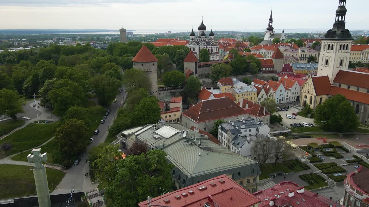 Drone fly above iconic medieval architecture of Tallinn Old Town, Estonia Hanseatic city. View over picturesque cityscape of historical buildings, church towers in the skyline during summer cloudy day