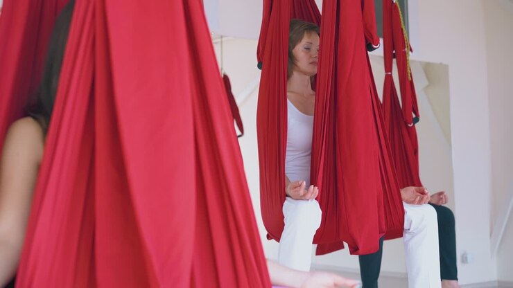 Kvinder sidder og slapper af i sommerfugle anti-tyngdekraft yoga asana