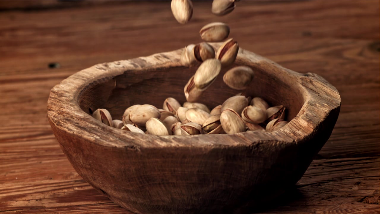Pistachios Falling into a Rustic Wooden Bowl in Slow Motion