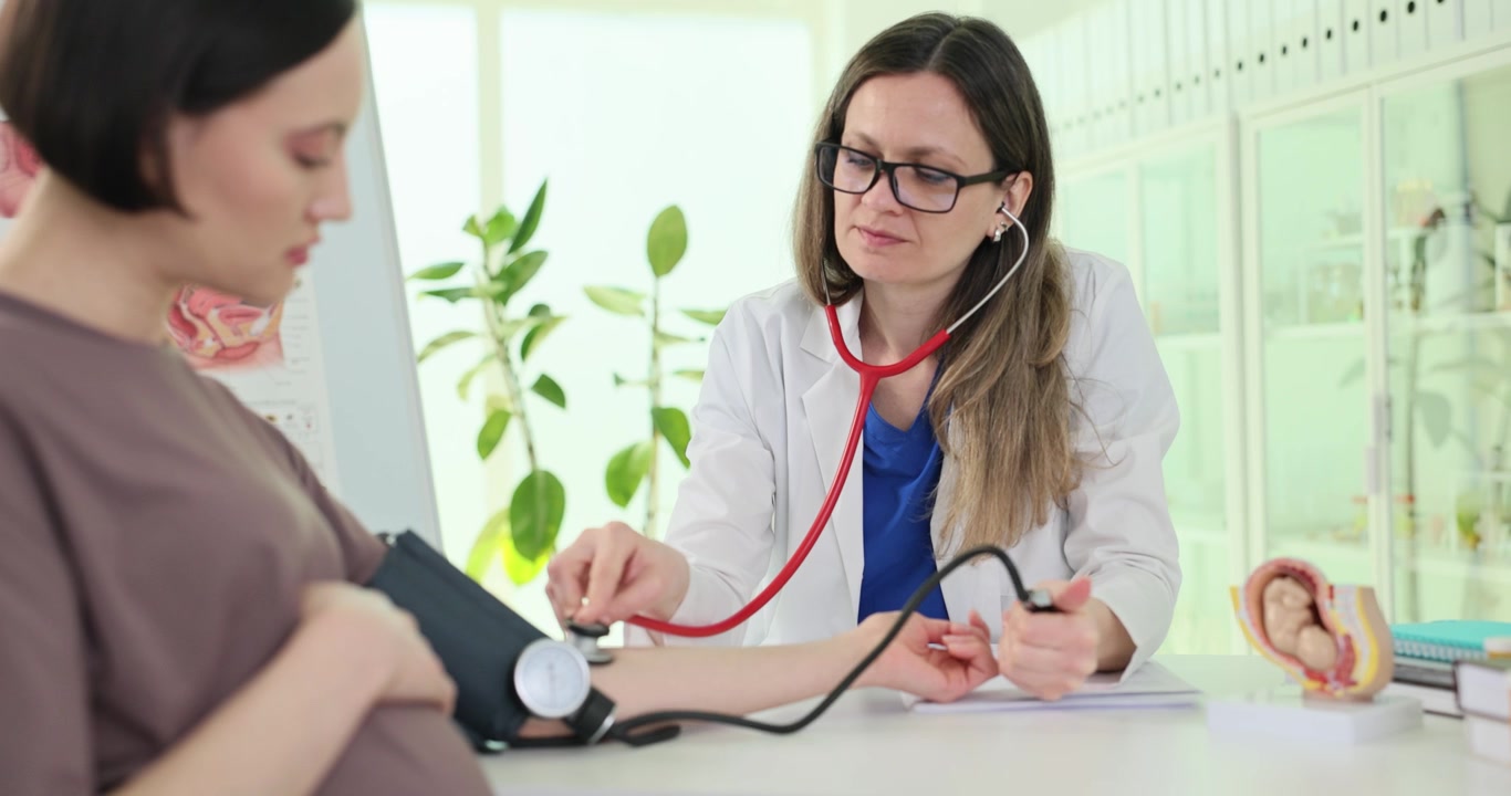 Blonde family doctor measures blood pressure of pregnant woman