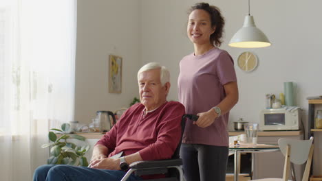 portrait of caregiver and elderly man in wheelchair