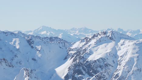 lines of snowy alpine massif, full of rocky peaks, sunny, winter day in the alps- pan shot