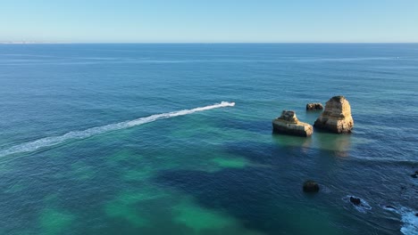 Lancha-Rápida-En-La-Costa-Rocosa---Algarve,-Portugal---Droneview-Estabilizado-En-4k