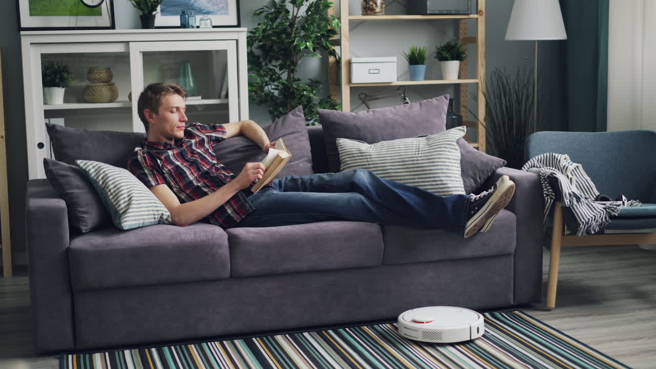 Man Relaxing on Couch and Reading a Book in a Cozy Living Room