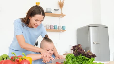 Happy Mother and her Little Son Cooking Vegetable Food in Modern White Kitchen Happy Mother and her Little Son Cooking Vegetable Food in Modern White Kitchen a Little Boy with a Stylish Hairstyle