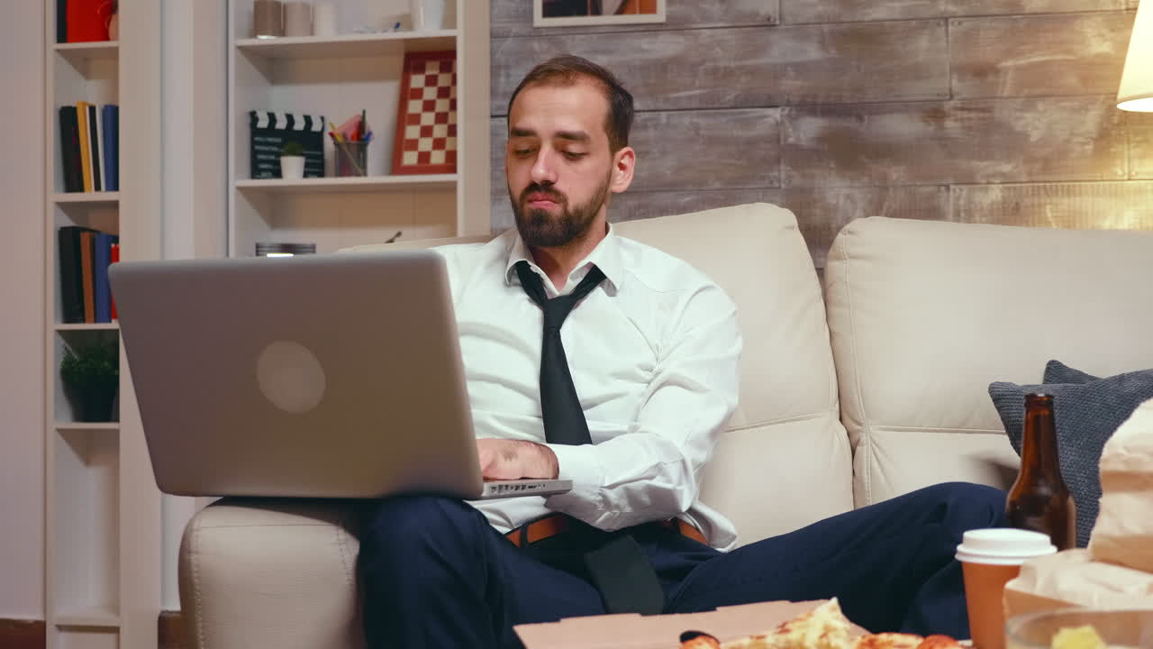 Tired businessman in living room working on laptop