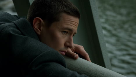 pensive man leaning on bridge railing
