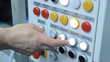 la mano humana presionando botones para iniciar la línea de producción en la fábrica