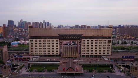 aerial shot of railway station building standing out with city skyline in the background on a cloudy day, hangzhou, china