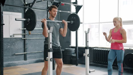 man weightlifting in gym with trainer