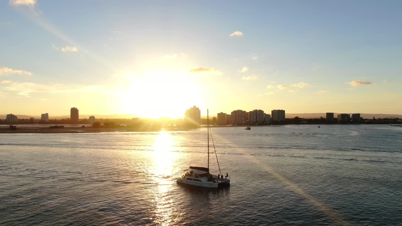 Catamaran motoring slowly on Gold Coast waterways,Sunset reflection on water.Labrador in background