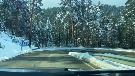 Lapso-De-Tiempo-Desde-El-Interior-De-Un-Coche-Conduciendo-Por-Una-Carretera-De-Montaña-Con-árboles-Nevados-A-Su-Alrededor