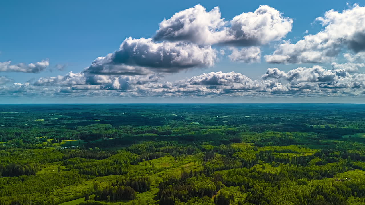 Cloud shadows drifting across green forests and wide open farmland, static high panoramic overview of climate changing and clouds swirling