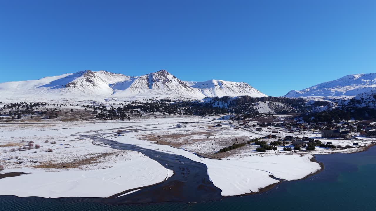 Aerial view of snowy Caviahue landscape with Andes mountains and frozen river, Neuquen, Argentina