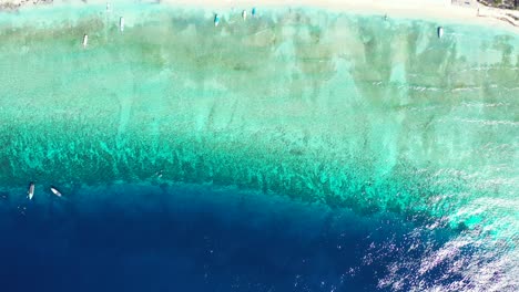 small boats sailing around calm clear shining water of blue turquoise lagoon near shore of tropical island, caribbean