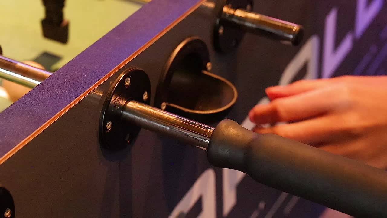 Detailed view of a foosball handle being skillfully maneuvered by a player's hand.