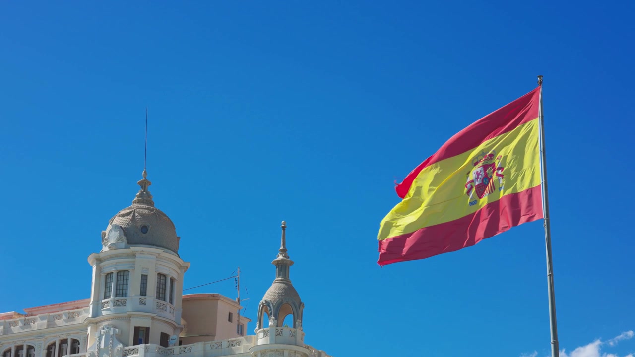 Spansk flag vajende foran gammel bygning i Alicante
