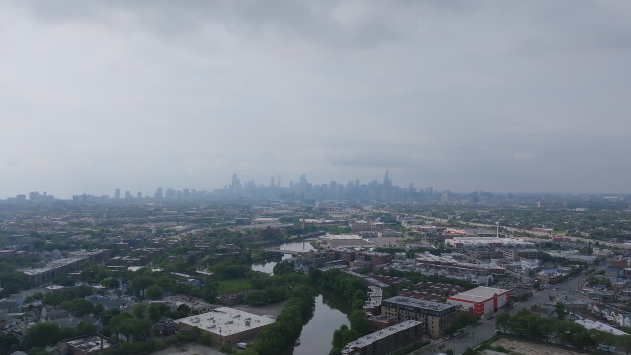 Aerial view of Chicago's cityscape with river and distant skyline under cloudy skies