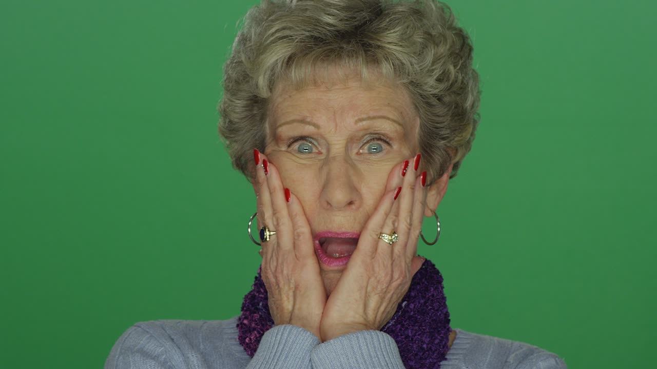 Older woman looking shocked and appalled, on a green screen studio background