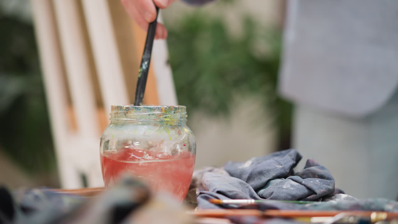 예술가는 유리 항아리에 부어 놓은 물에 을 고, 미술 선생님은 상점의 테이블에서 빨간 색소에서 을 청소합니다.