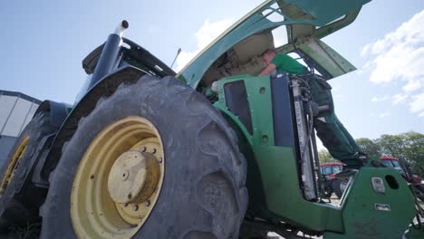 farmer mechanic repairing tractor. open tractor hood, engine. repair agricultural technology