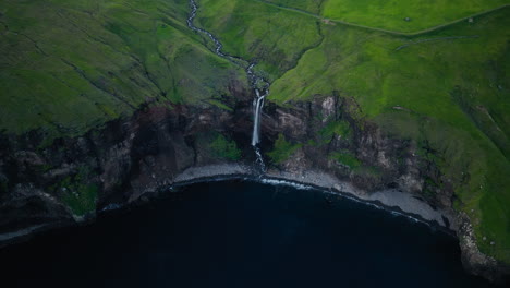 Majestic Waterfall Cascading from Lush Green Cliffs into the Ocean