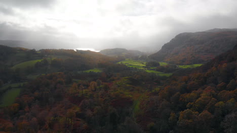 Imágenes-Aéreas-De-Tejo-Tarn-En-Cumbria-En-Dirección-Al-Agua-De-Coniston-Sobre-El-Bosque-En-Sus-Colores-Otoñales