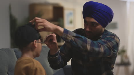 vader gebruikt salai naald om haar weg te regelen bij het binden van turban op het hoofd van jonge sikh zoon zit op de bank opgenomen in real time 1