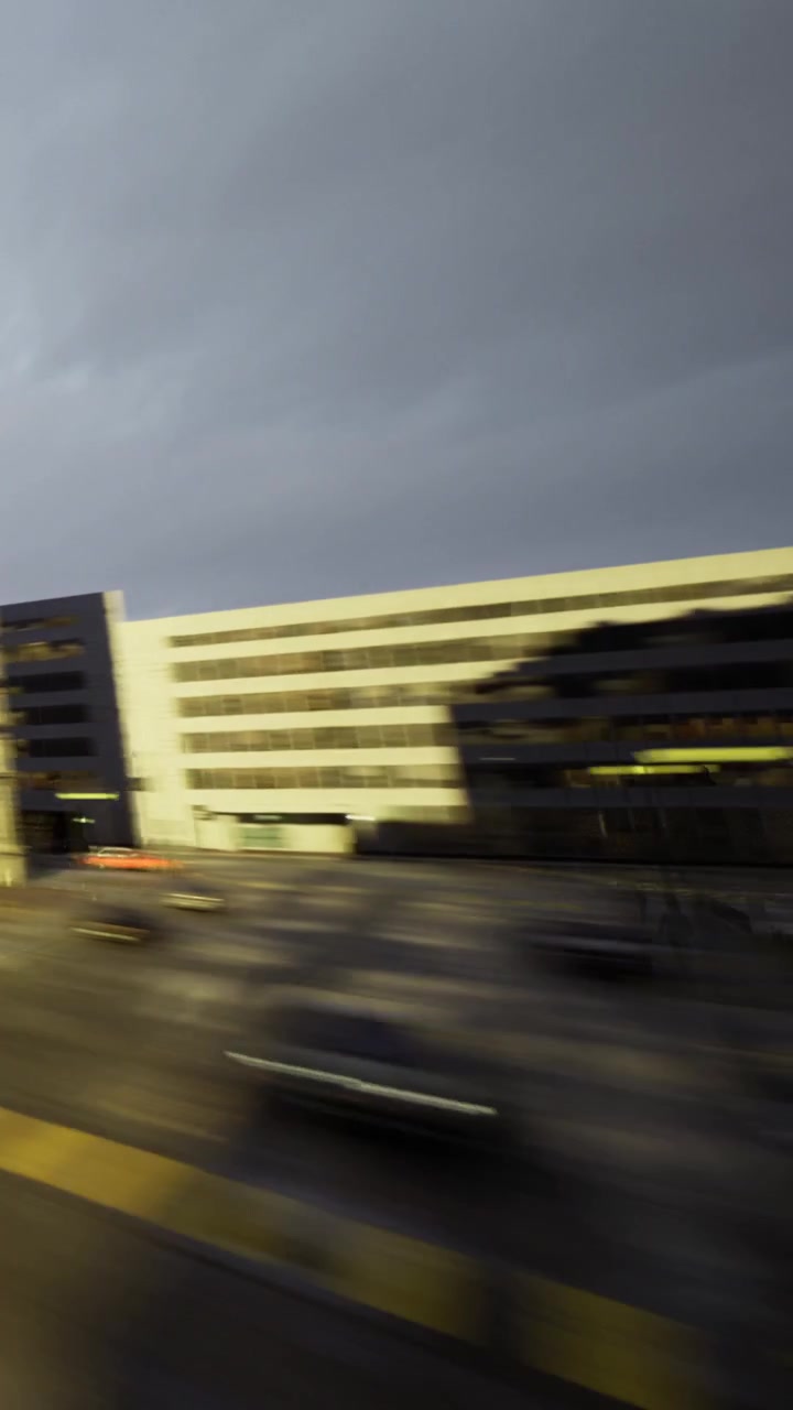 Kaupungin siluetti hehkuu iltavaloissa junan kiitäessä ohi värikkäiden rakennusten