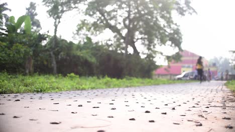 Young-girl-jogging-on-road-going-away-from-camera-at-morning-sunrise-or-evening-sunset,-low-angle-shot