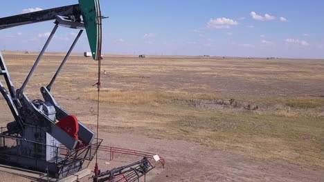 asno asintiendo pumjack asintiendo en la pradera plana, recogiendo petróleo crudo