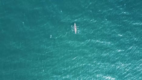 Solo-Rowing-boat-out-at-Sea,-off-the-coast-of-the-United-Kingdom-on-a-sunny-day,-filmed-with-a-DJI-mavic-drone,-which-is-directly-above,-alienating-the-single-boat