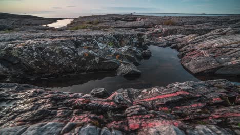 el sol se pone en el horizonte, proyectando su reflejo en las tranquilas piscinas de marea rodeadas de rocas de colores marchitos.