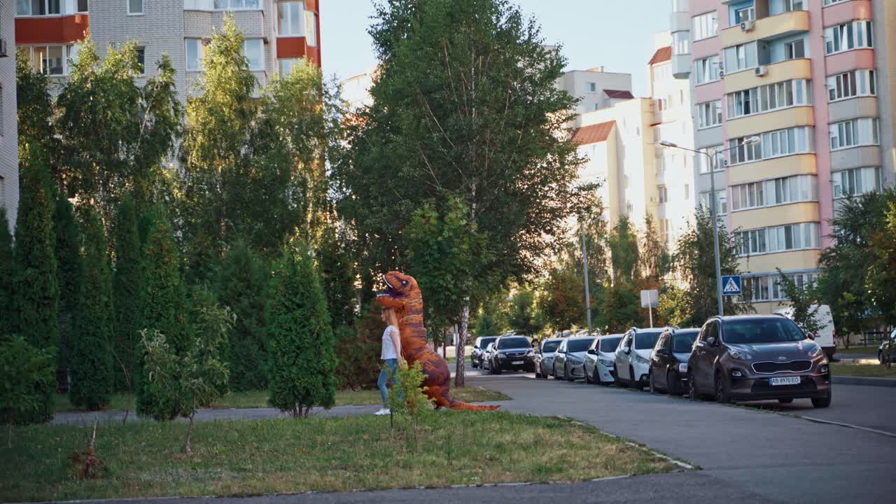 Person in dinosaur costume. Person in t rex costume walking with girl at city street