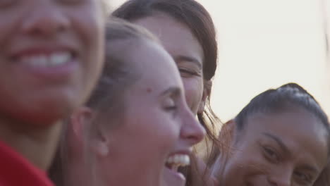 retrato de equipos de fútbol femenino celebrando con los brazos alrededor el uno del otro después del juego