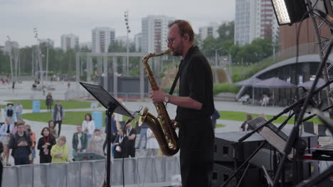 saxophonist performing outdoor concert in city park