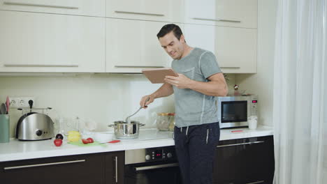 Happy-man-cooking-healthy-dinner-at-home-kitchen-with-tablet.