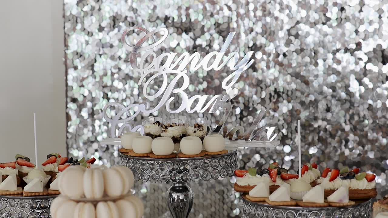 Variety of desserts arranged on a table with a shiny backdrop at a candy bar, creating a festive atmosphere