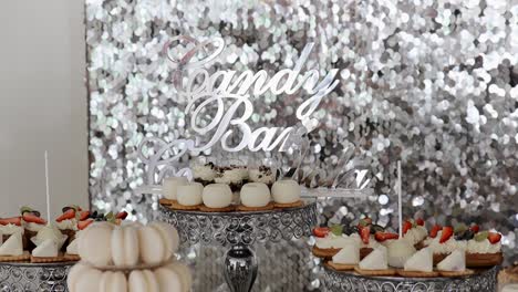 variety of desserts arranged on a table with a shiny backdrop at a candy bar, creating a festive atmosphere