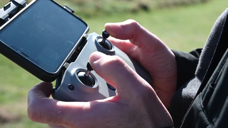 view of a remote control with two joysticks to control a drone, telephone attached