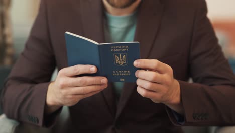 Close-up-of-a-man's-hands-taking-a-Ukrainian-passport-and-looking-at-it-against-the-background-of-a-man's-jacket