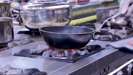 chef warms the oil in a pan before frying