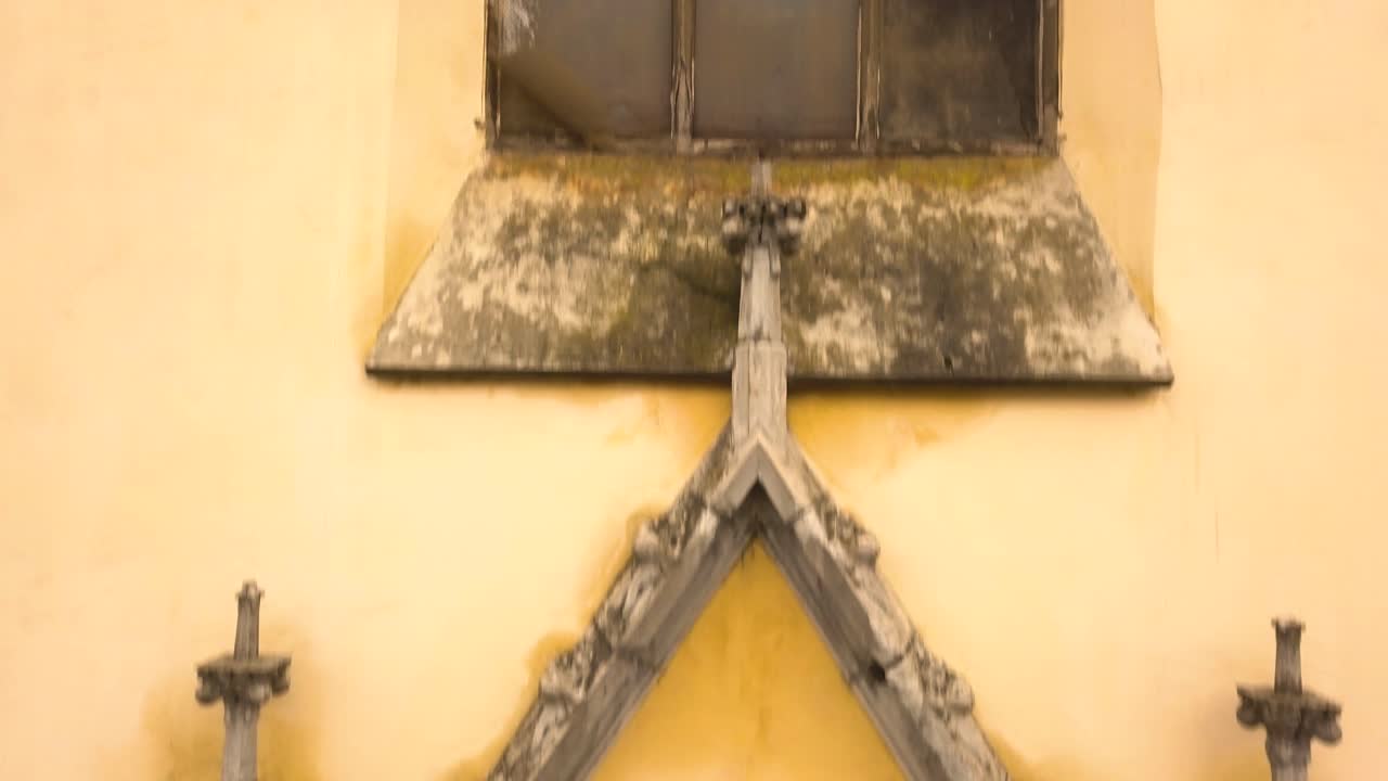 오후에 시기쇼아라 시에 있는 빈티지 건축 교회의 입구와 그 위의 큰 창을 캡처하는 받침대 위쪽 드론 샷