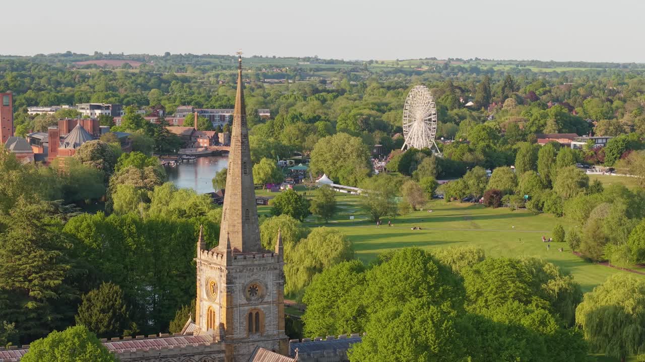 Um Recuo de Drone sobre a Exuberante Paisagem Primaveril de Stratford-upon-Avon, Revelando Gradualmente a Majestosa Igreja Gótica da Santíssima Trindade Aninhada entre Árvores em Flor e o Rio Avon