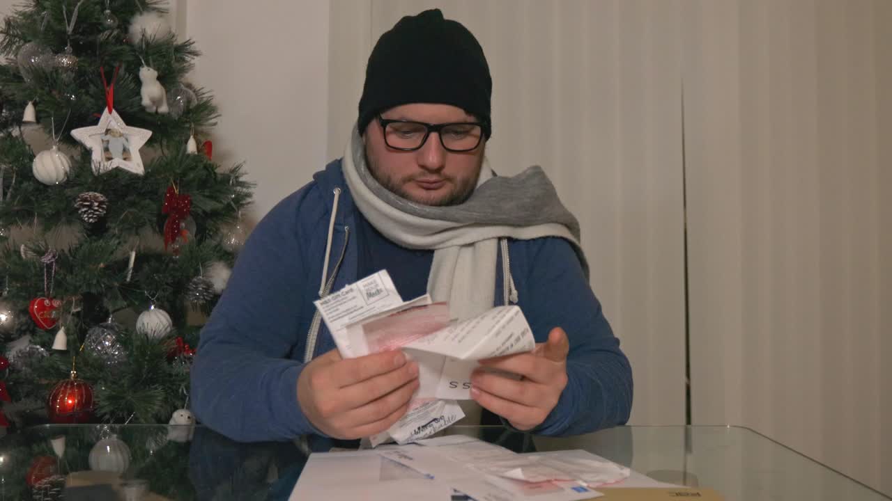 Uomo stressato seduto alla scrivania, che esamina le bollette da pagare una per una.