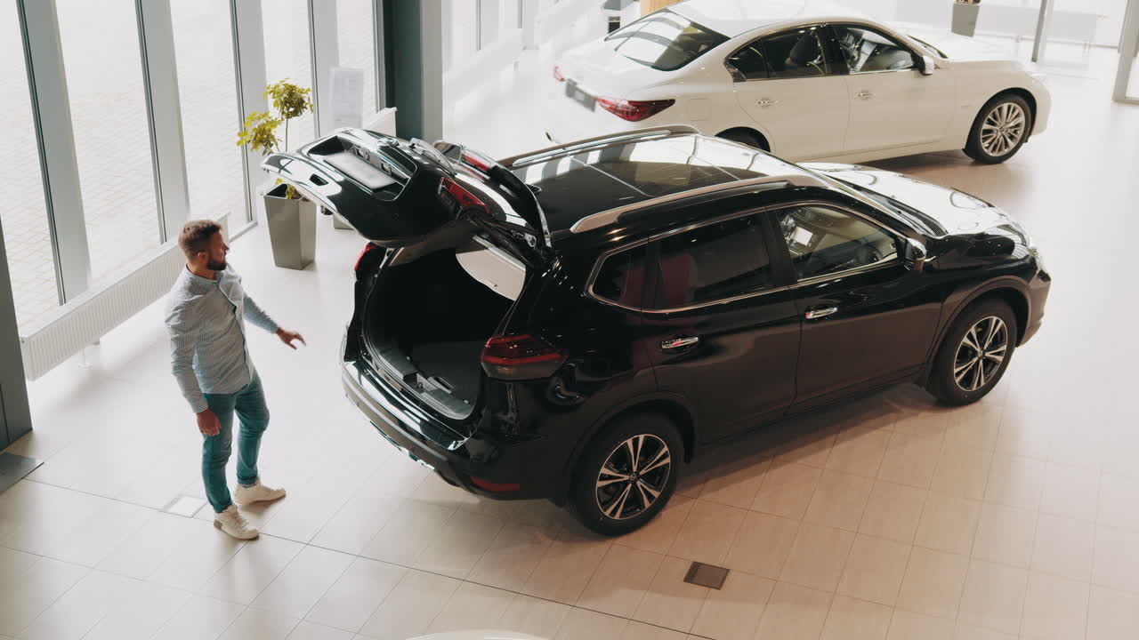 남자 는 자동차 전시실 에서 검은 suv 를 보고 있다