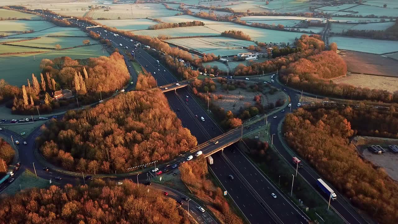 Drone Aerial View Of A Busy Motorway Junction Flying Forwards In With Cars And Trucks In The Winter With Orange And Brown Trees